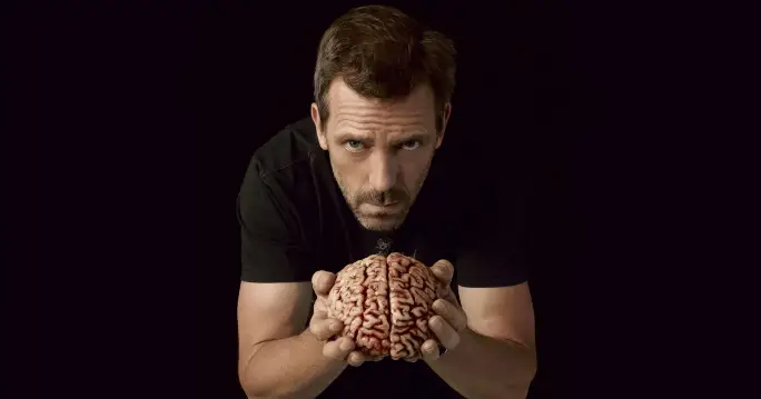 A man, Gregory House MD, holding a brain in his hands.