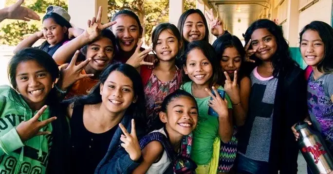 A group of young teenagers posing for a photo during  a playing for change video