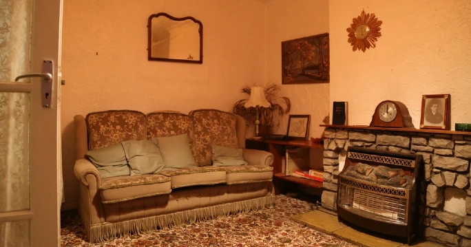 A living room showcasing a fireplace and couch, capturing the unsettling essence of the Pritchard family's haunting at 30 East Drive.