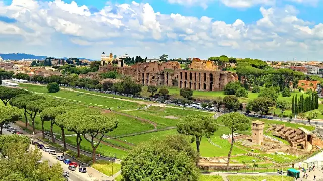 A panoramic view of the Roman Forum and Colosseum, with the ancient remains of the Circus Maximus in the foreground.